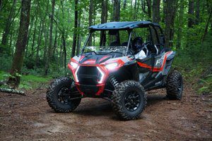 A red and black four wheeler parked in the woods.