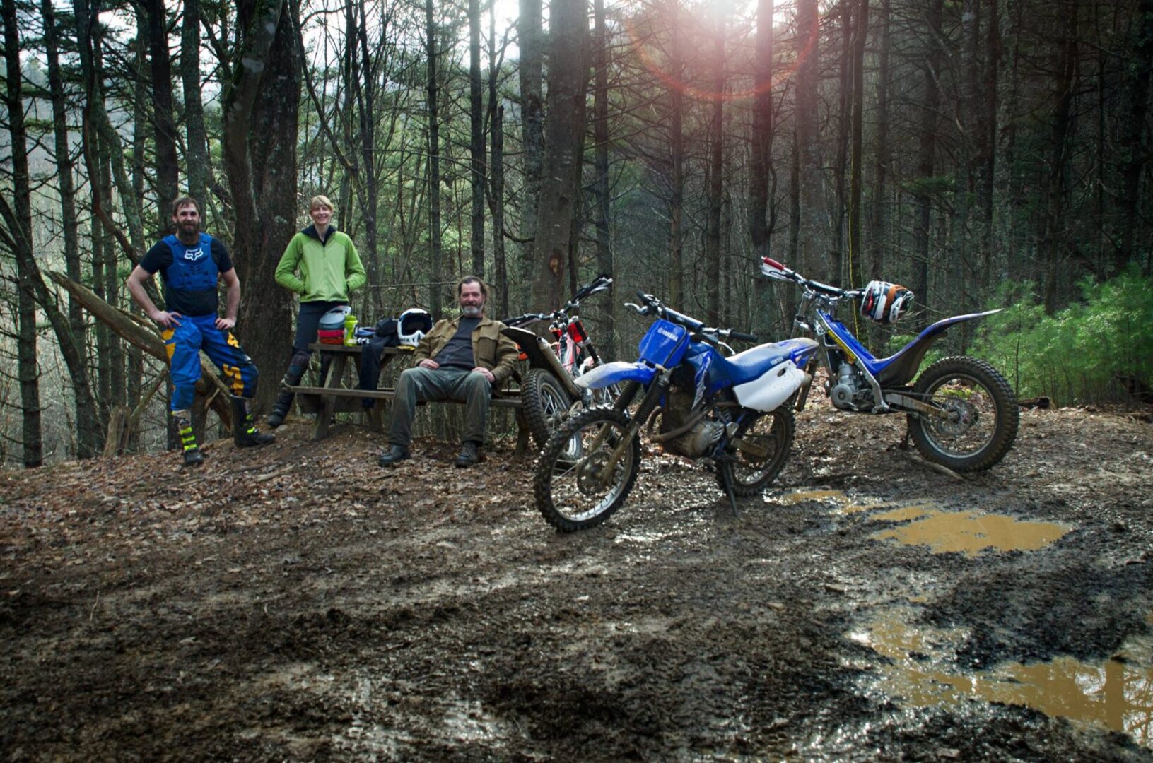 A group of people sitting around a dirt bike.
