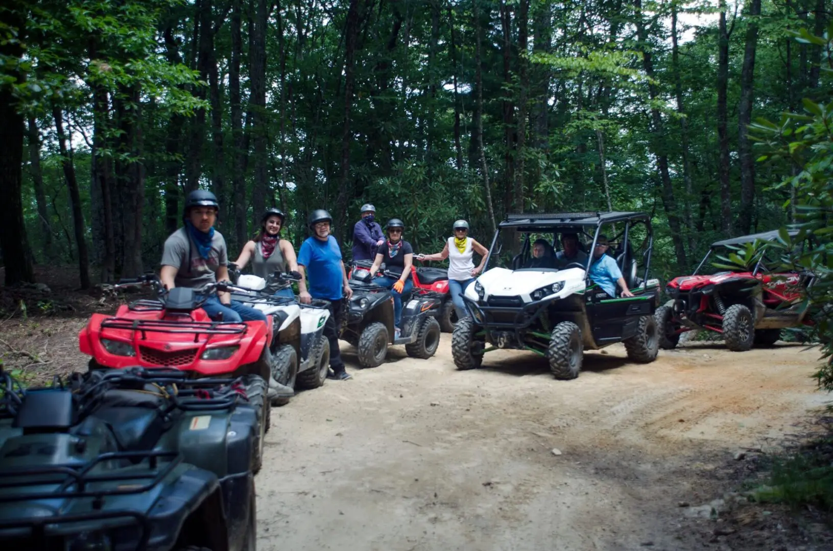 A group of people on atvs in the woods.