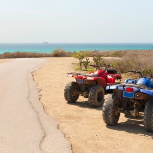 Two atvs parked on the side of a beach.