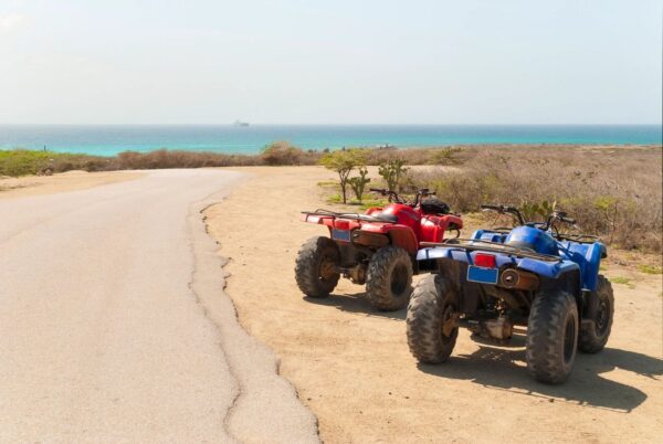 Two atvs parked on the side of a beach.