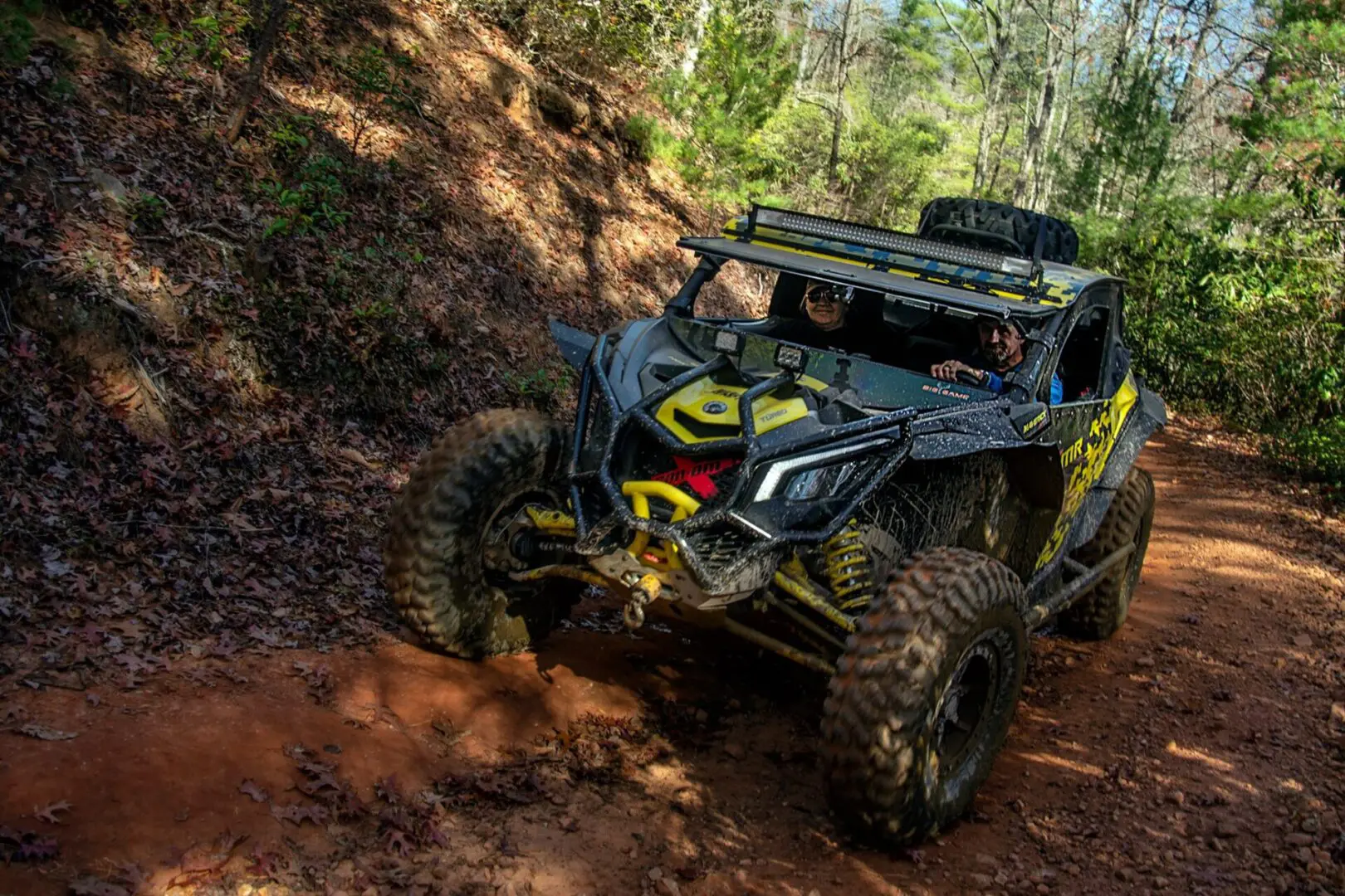 A yellow and black four wheeler driving down the trail.